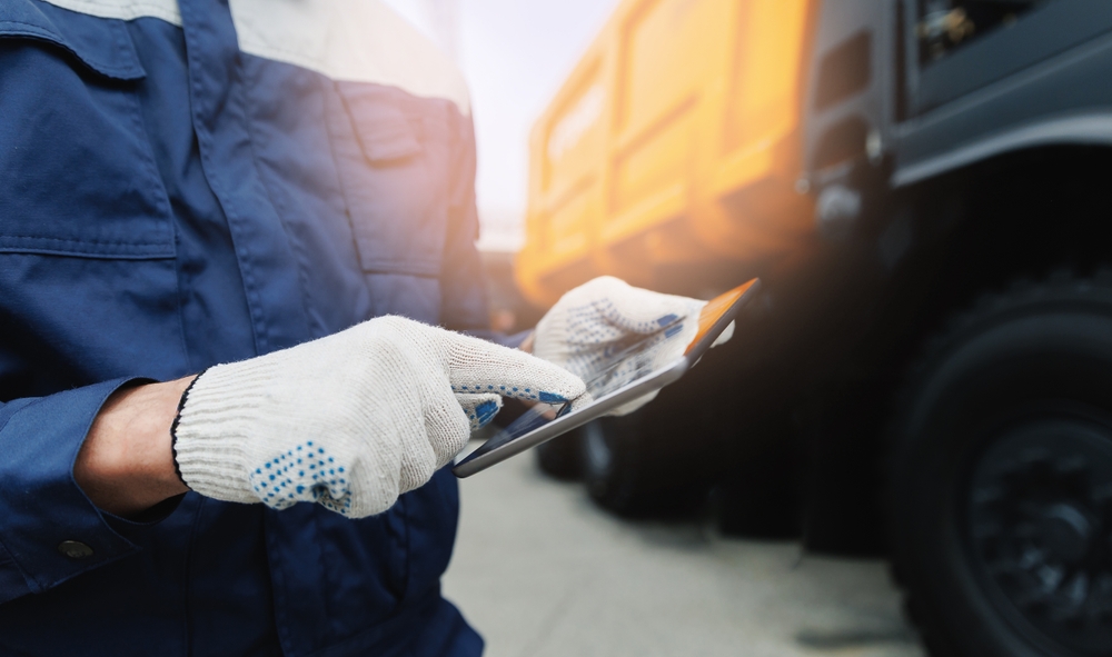 Driver,Man,In,Uniform,With,Tablet,Computer,Controls,Dump,Truck.