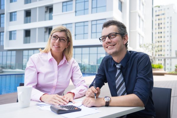 smiling-ambitious-accountants-sitting-table-with-papers-calculator-scaled.jpg
